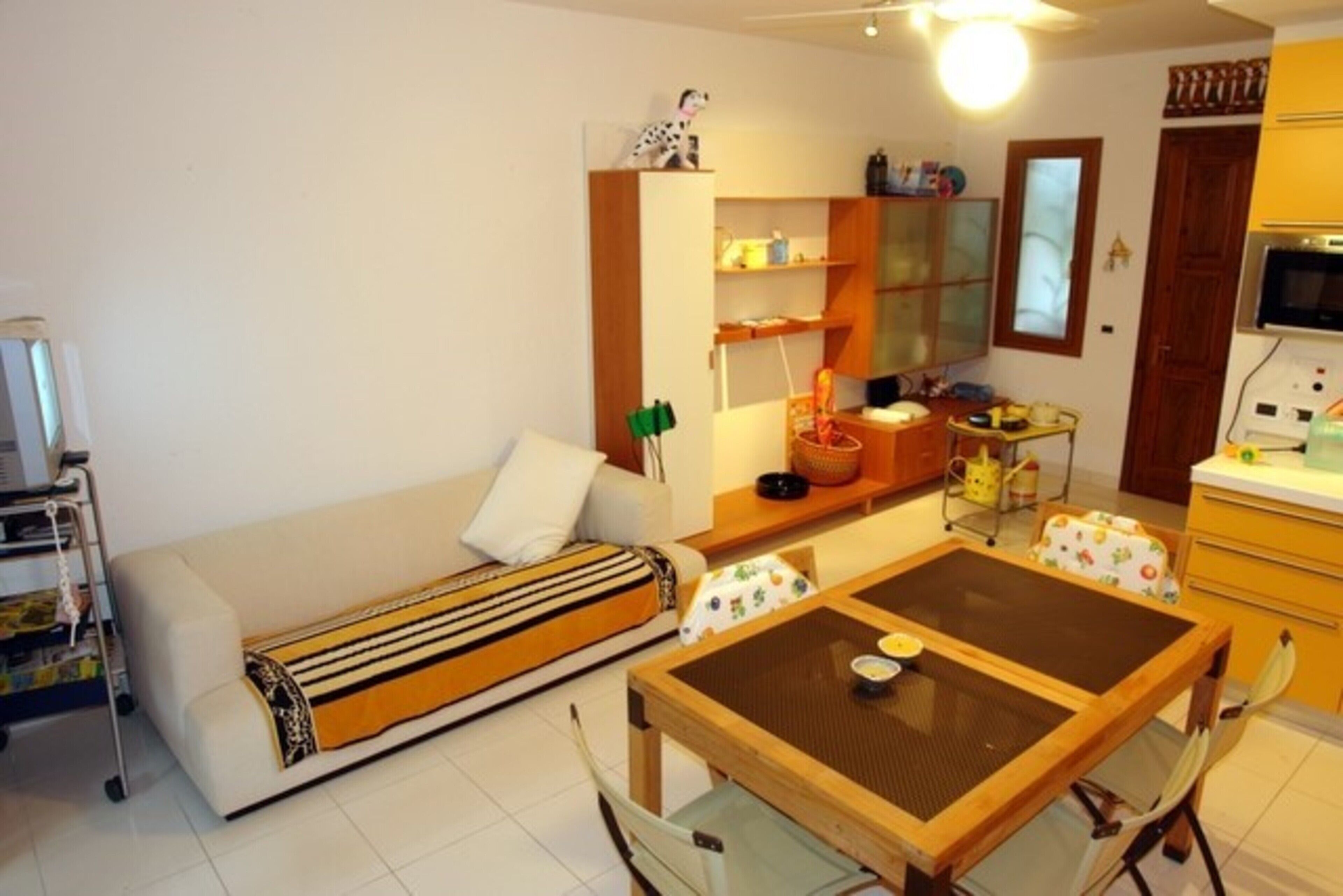 A compact living space with a sofa, a dining table, a kitchen area, and a small cabinet.