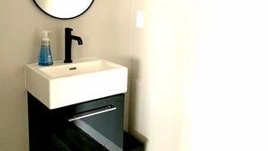 A bathroom with a white sink, black cabinet, and a mirror.
