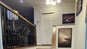 Un escalier avec une rampe en bois, un tapis noir en bas et une porte blanche en haut.