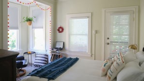 Un dormitorio con cama, escritorio, silla y ventana con persianas.