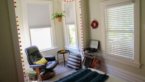 Una habitación acogedora con un sillón de cuero, una mesita y un ventanal con persianas.