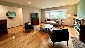 Amplia sala de estar con un sofá, dos sillones, una mesa de centro y un televisor.