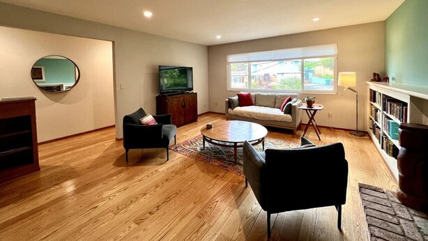 A spacious living room with a sofa, two armchairs, a coffee table, and a TV. - Charming 3 BR Home Near Redwood Park w/ Bay Views (Oakland)