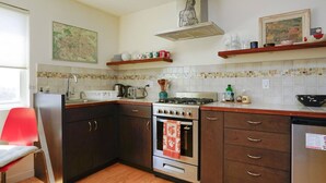 Una cocina con armarios de madera oscura, una estufa a gas, un lavabo y una silla roja.
