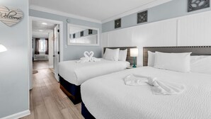 Habitación de hotel con dos camas, un espejo grande y un cartel de 'Welcome'.