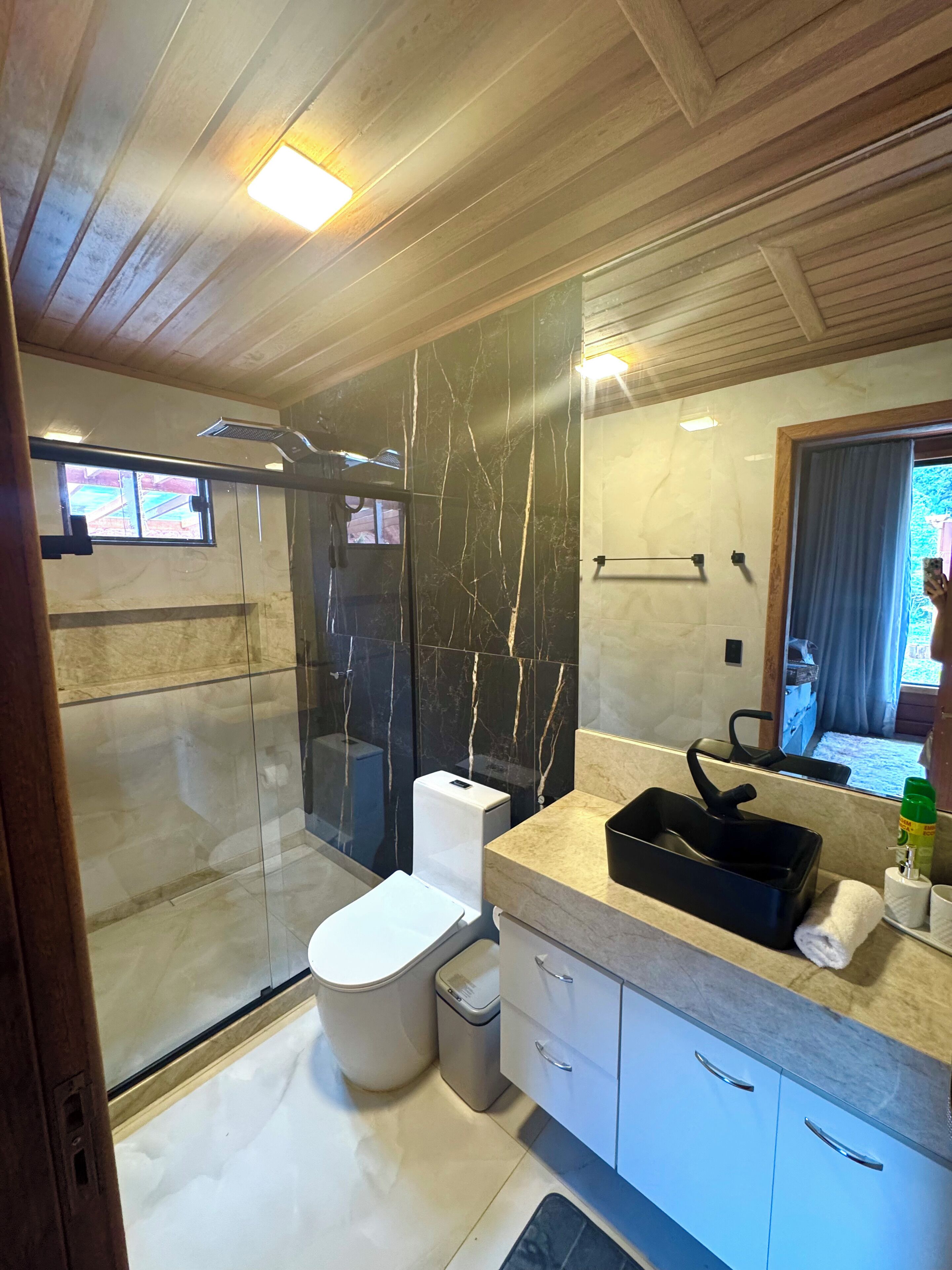 Een moderne badkamer met een douchecabine van glas, een toilet en een wastafel met spiegel.