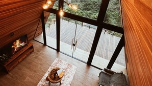 Una habitación acogedora con techo de madera, un ventanal grande, chimenea y un sofá.