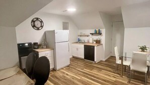 Moderni keittiö, jossa on ruokailutila, puulattia ja valkoiset keittiökaapit.