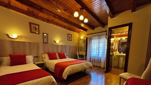 A hotel room with two beds, wooden flooring, and a bathroom visible through an open door. - Hostal Noguera (Llavorsí)