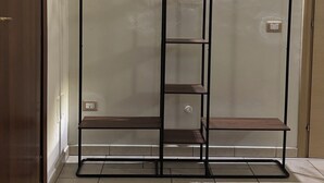 Une chambre comprenant une armoire, un lit et une étagère murale avec des porte-manteaux.