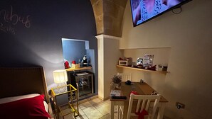 Une petite pièce agréable, dotée d’un lit, d’un bureau, d’une chaise, d’une télévision et d’un réfrigérateur.