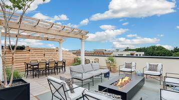 Eine Dachterrasse mit einer Pergola, Sitzgelegenheiten im Freien und einer Feuerstelle.