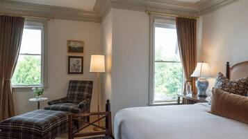 A hotel room with a bed, a chair, two lamps, and a small table with a vase of flowers.