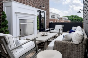 An outdoor patio with a fireplace, seating, and a view of the cityscape. - Hotel Burg (Leesburg)
