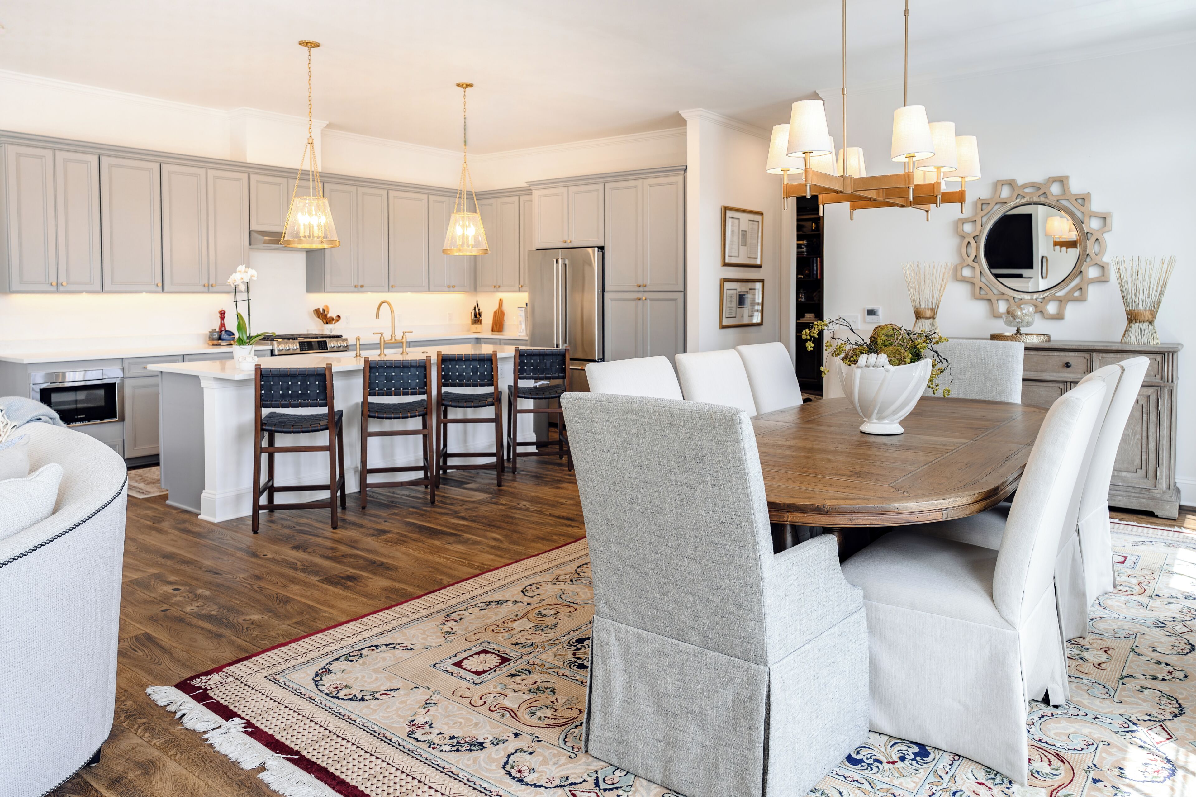 A modern kitchen with grey cabinets, a central island, and a dining area with a round table and chairs.