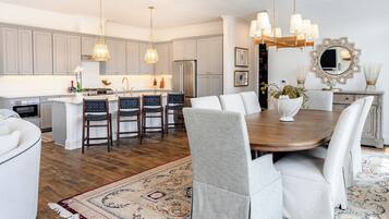 A modern kitchen with grey cabinets, a central island, and a dining area with a round table and chairs.