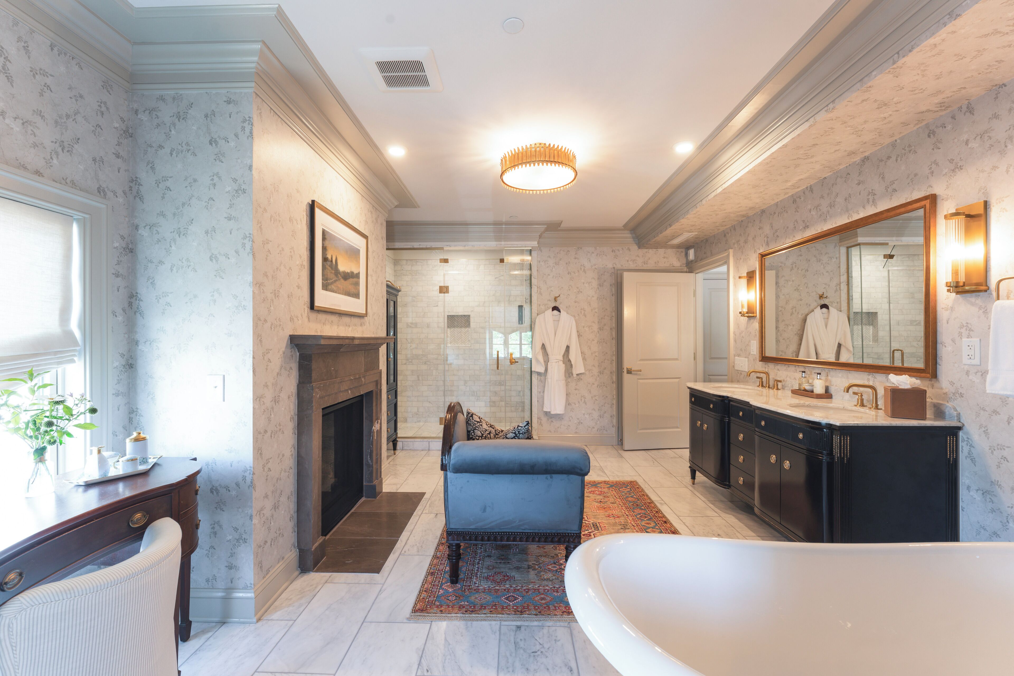 A spacious bathroom with a large bathtub, a double vanity, and a fireplace.