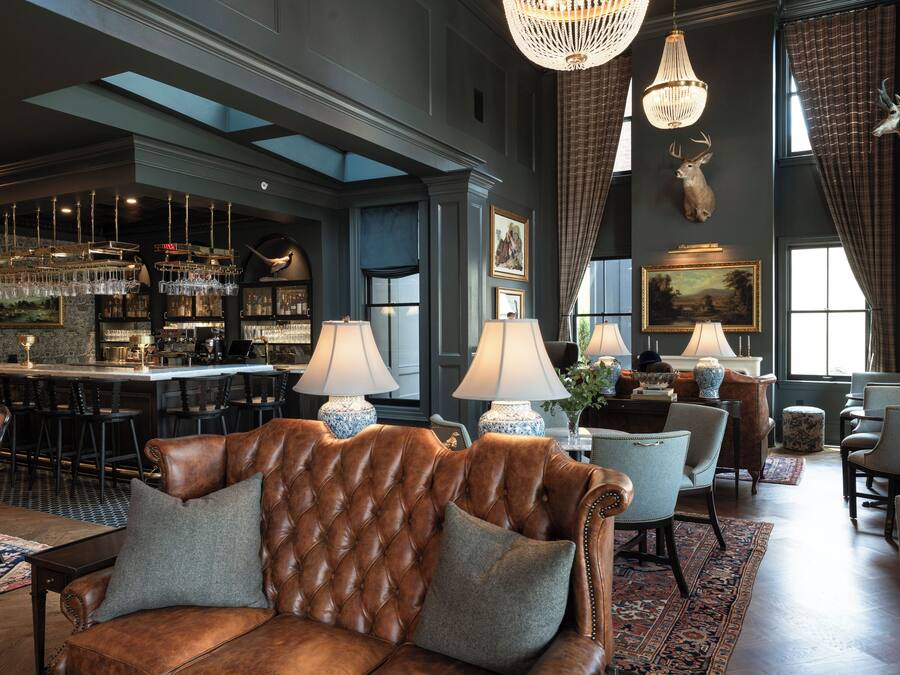 A spacious lounge with a leather sofa, bar area, and large windows.