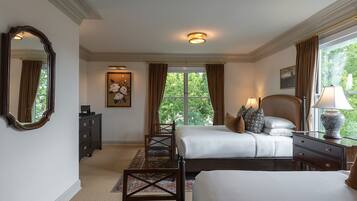 A hotel room with two beds, a dresser, a chair, a desk, and a large window with curtains.