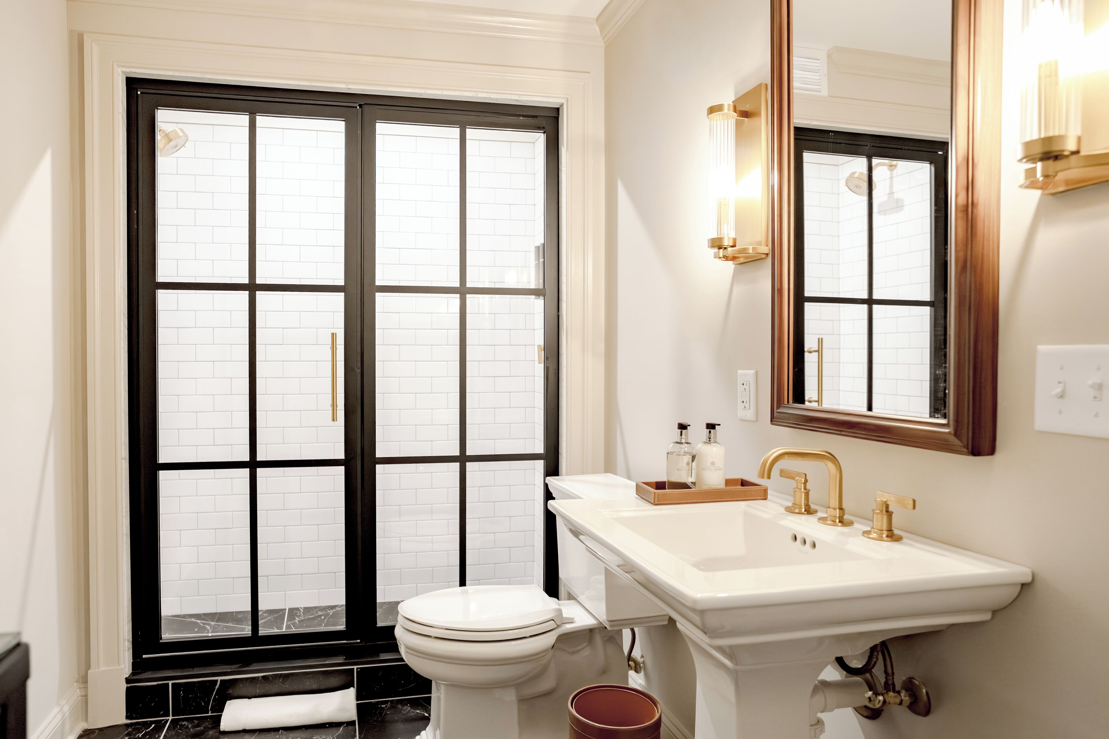 A bathroom with a white toilet, a sink with gold fixtures, and a large mirror.