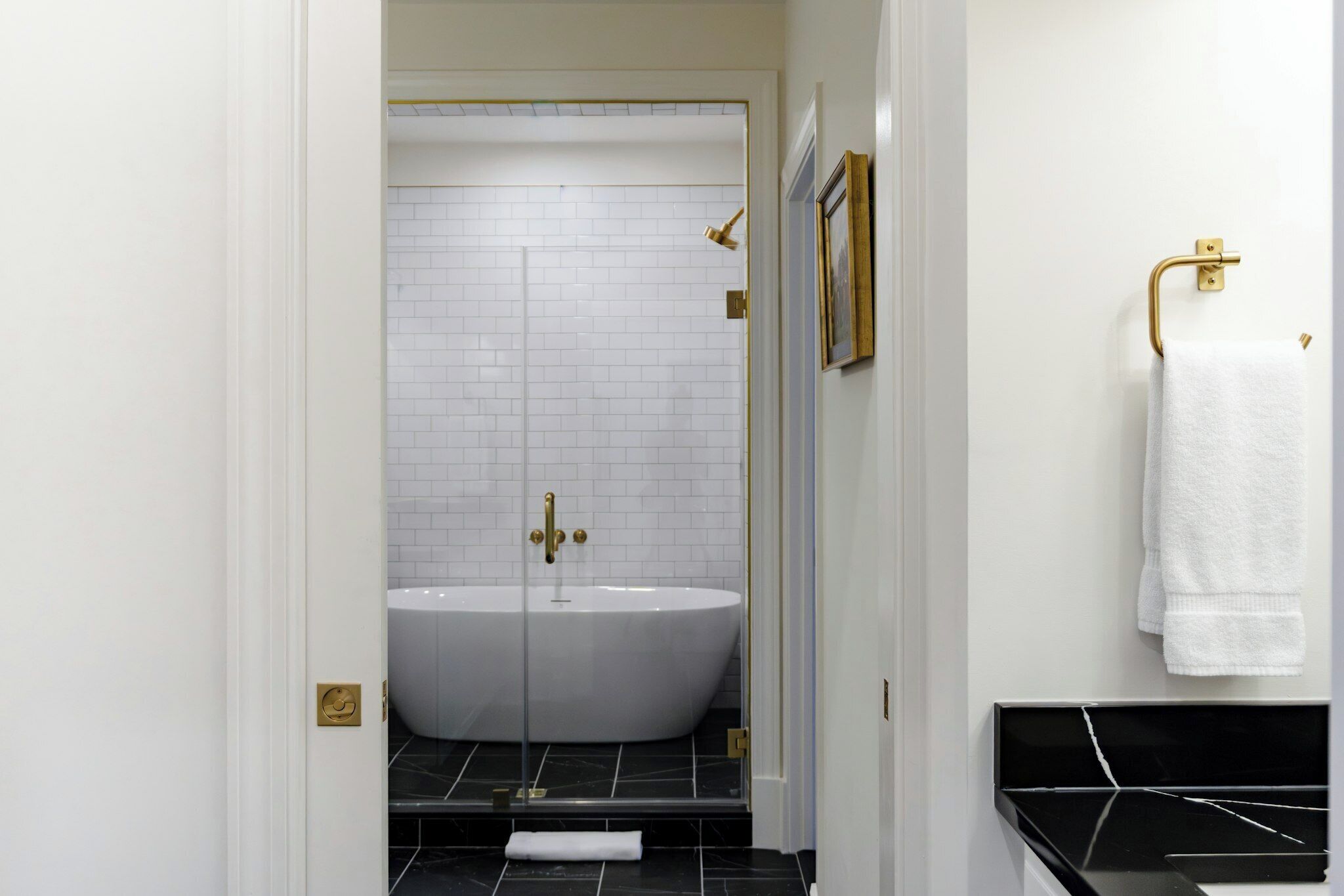 Une salle de bain moderne avec une baignoire sur pieds, une douche à l’italienne en verre et un comptoir en marbre noir.