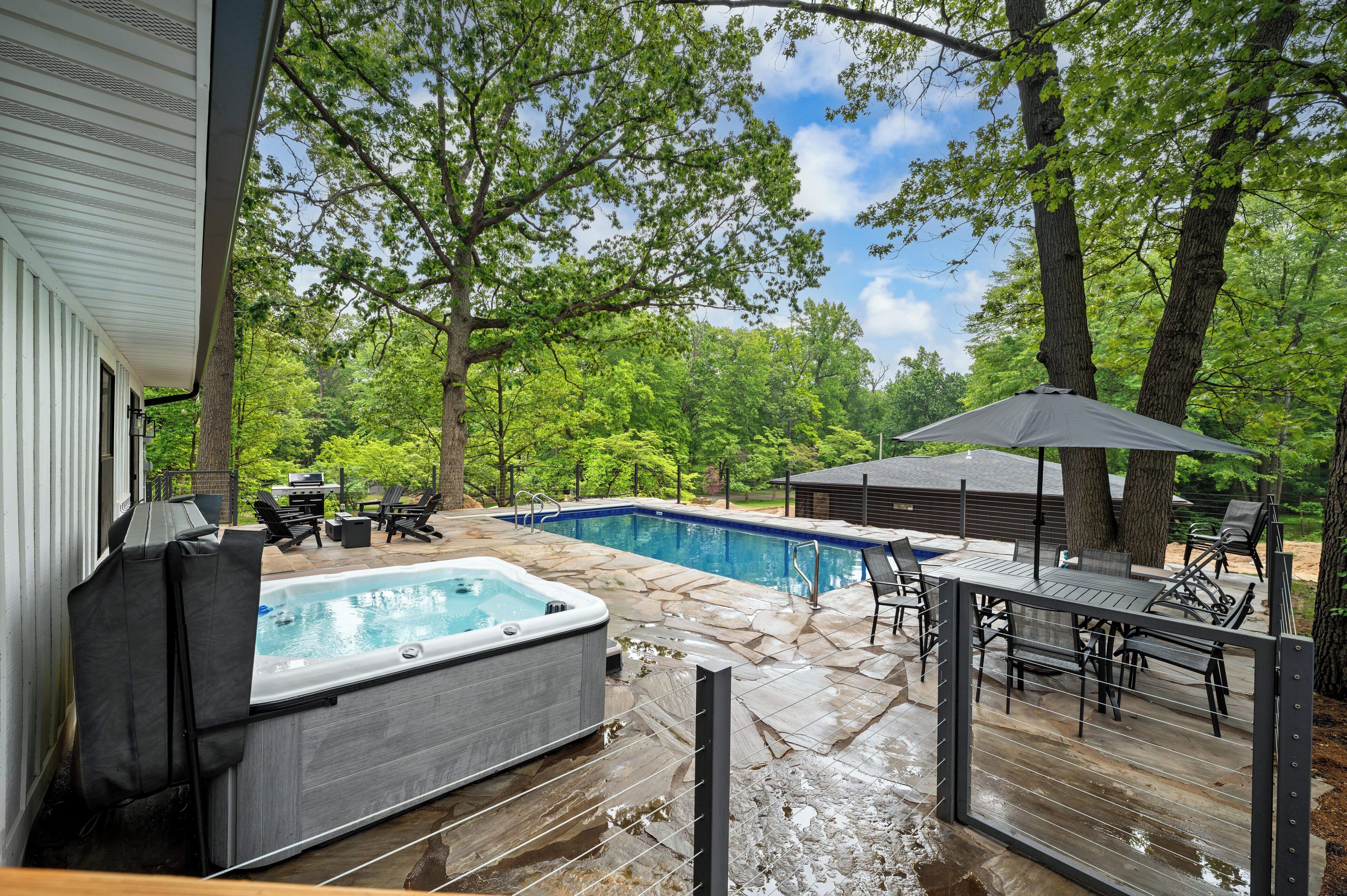 A backyard with a hot tub, a swimming pool, and outdoor furniture.