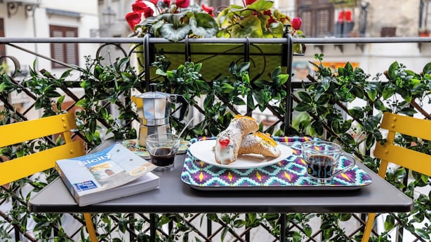 A table with a magazine, a plate with food, a glass of drink, and a decorative tray.