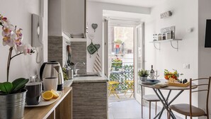 A modern kitchen with a built-in sink, a coffee maker, and a kettle. There is a small dining area with a table and chairs.