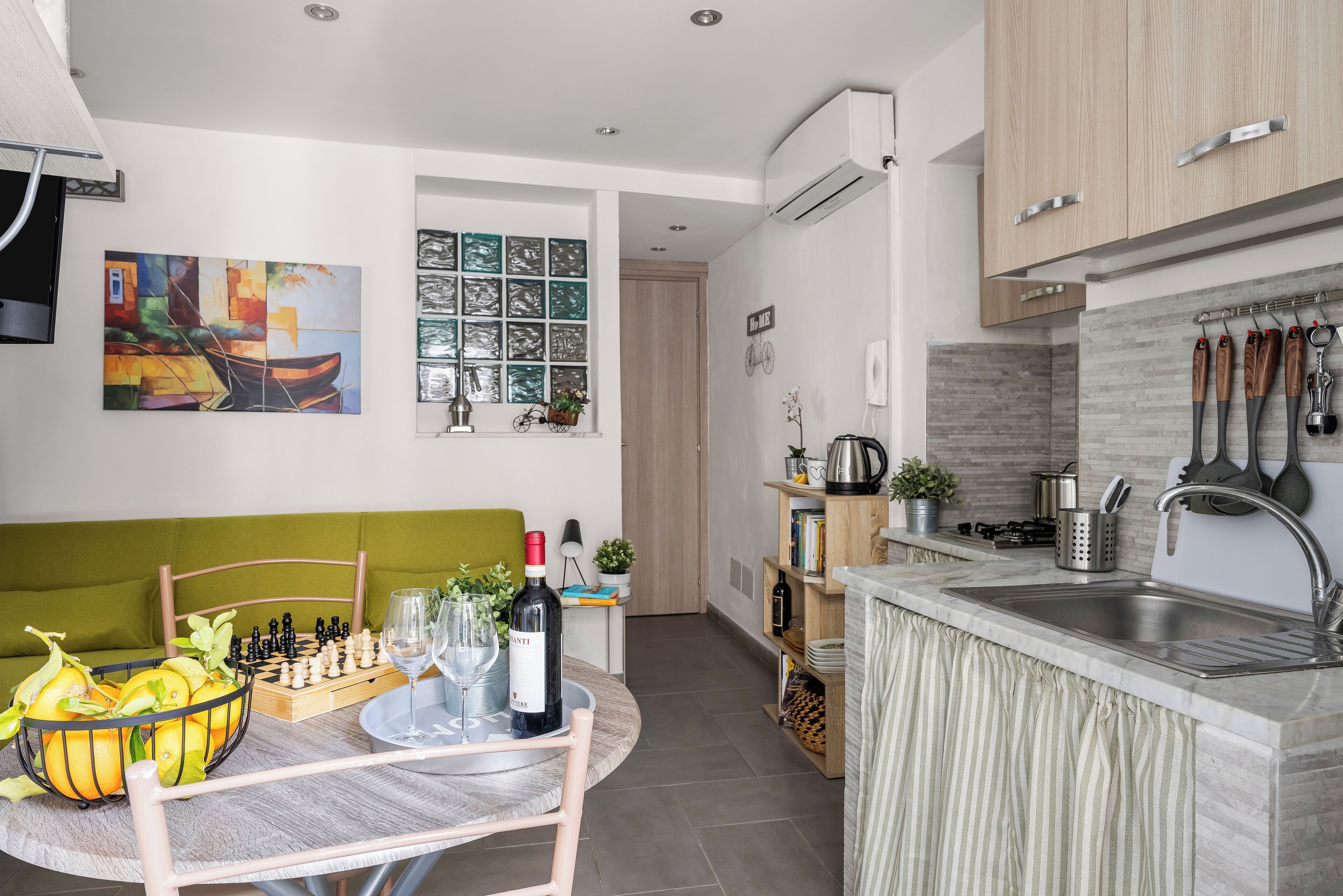 A modern kitchen with a built-in sink, wooden cabinets, and a dining area with a chessboard and wine.