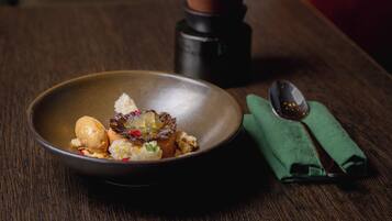 A bowl of food on a wooden table with a spoon and a green napkin.