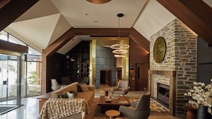 A spacious living area with a fireplace, modern furniture, and a view through large windows. - Coronet Ridge Resort (Arthur's Point)