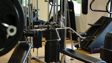 A gym with weightlifting equipment, treadmills, and a bench.
