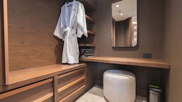 Un baño moderno con tocador de madera, un espejo y una bata colgada en un perchero.
