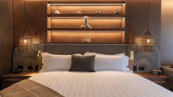 Una habitación de hotel moderna con una cama grande, cabecero de madera y luces colgantes.