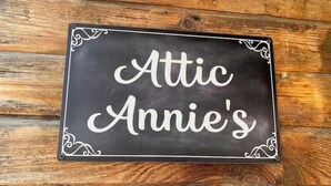 Une plaque noire avec du texte blanc en caractères cursifs sur un fond en bois.