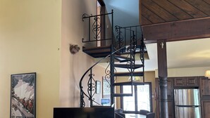 Un salon doté d’un escalier en colimaçon, d’un téléviseur à écran plat, de meubles en bois et d’une grande fenêtre.