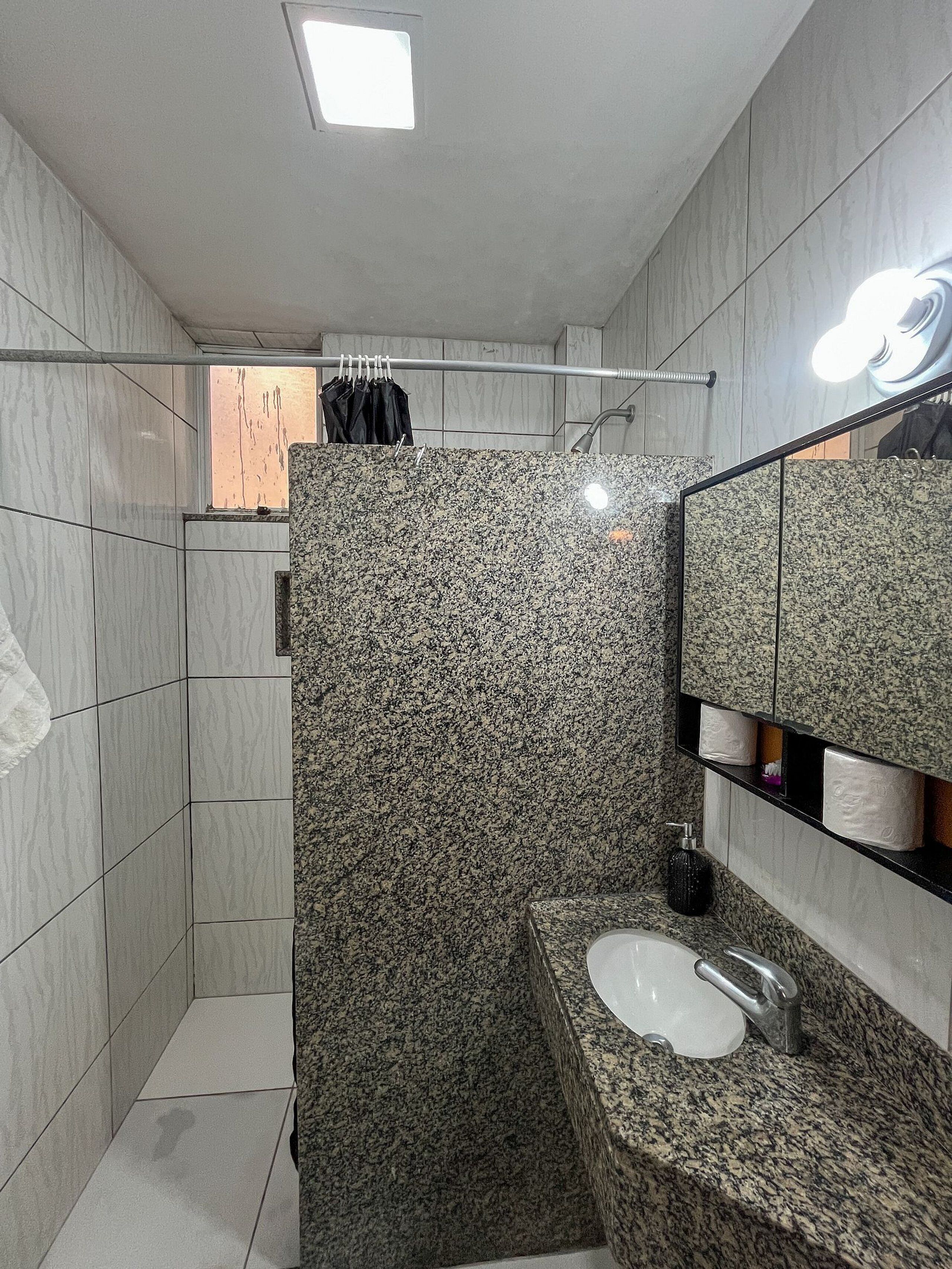 Un baño moderno con cabina de ducha de granito, un lavabo con grifo y un espejo con iluminación.