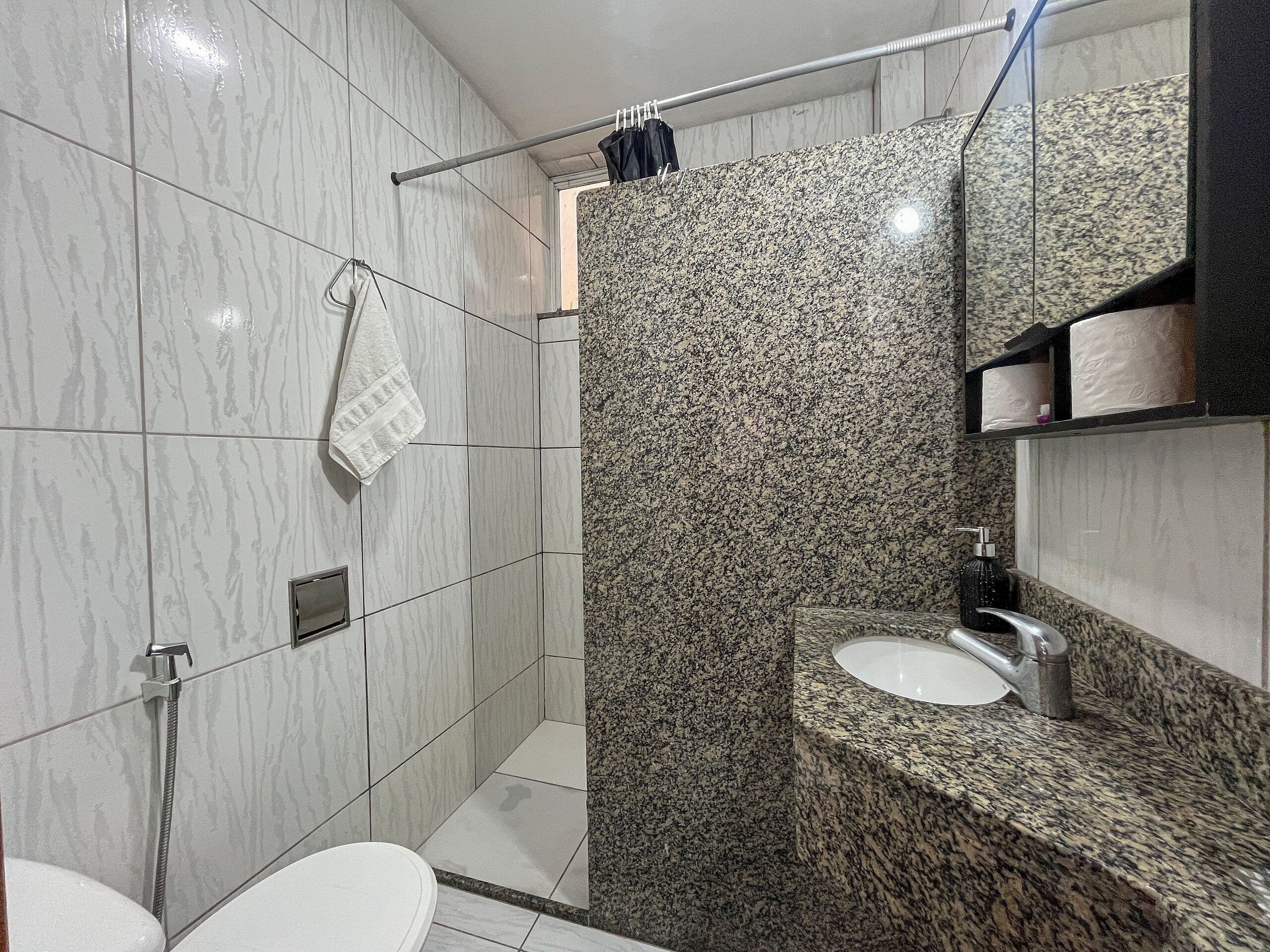A modern bathroom with a shower, toilet, and granite countertop sink.