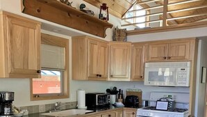 A kitchen with wooden cabinets, a microwave, a stove, and a coffee maker. - Cabin #23 at Hyatt Lake Resort (Jackson County)