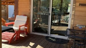 A wooden deck with outdoor seating, including a red chair and a table. - Cabin #23 at Hyatt Lake Resort (Jackson County)