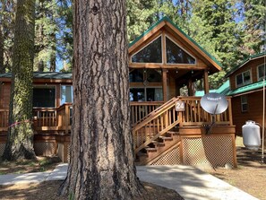 Une cabane avec une façade en bois, un balcon et un escalier menant à l’entrée.