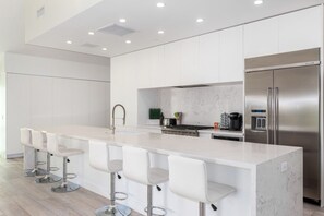 A modern kitchen with a central island, stainless steel appliances, and white cabinetry.