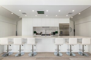 A modern kitchen with a central island, bar stools, and stainless steel appliances.