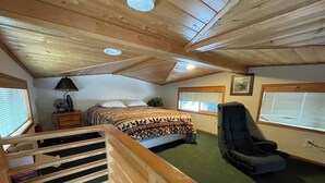 A room with a bed, a massage chair, a wooden staircase, and a window with blinds. - Cabin #18 at Hyatt Lake Resort (Jackson County)