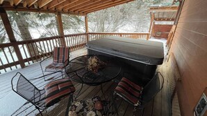A covered outdoor deck with a barbecue grill, metal chairs, and a table. - Cabin #18 at Hyatt Lake Resort (Jackson County)