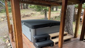 Een hottub onder een houten pergola, met een trap ernaartoe.