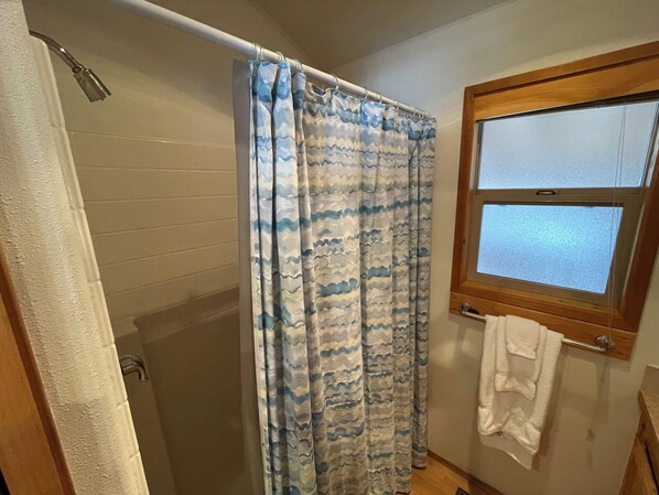 Une salle de bain avec un rideau de douche, une fenêtre et un porte-serviettes.