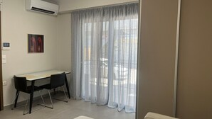 A room with a desk, two chairs, a bed, and a window with sheer curtains. - Petite Fleur Apartment (Lefkada)
