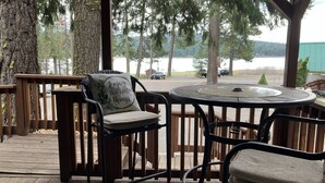 Un espacio de estar al aire libre cubierto con una mesa y sillas, con vista a un cuerpo de agua.