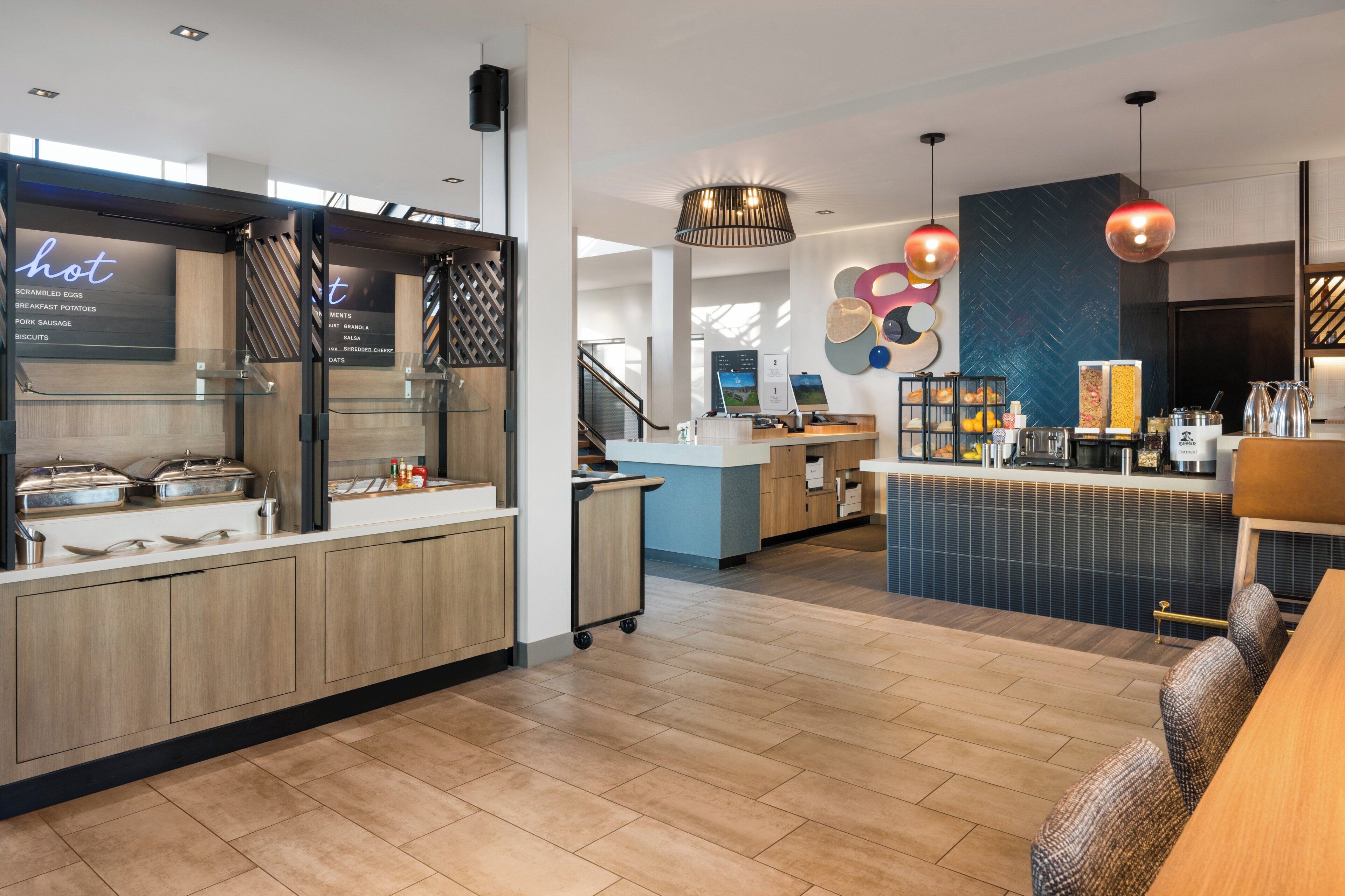 A modern kitchen area with a breakfast bar, a coffee station, and a seating area with a sofa and table.